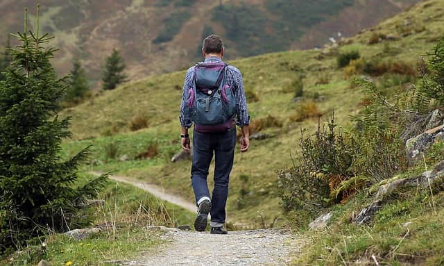 Photo of a man walking on a path in the mountain, taken from behind. The Big Picture Event Storming opens up a lot of opportunities and is just the beginning of the path.