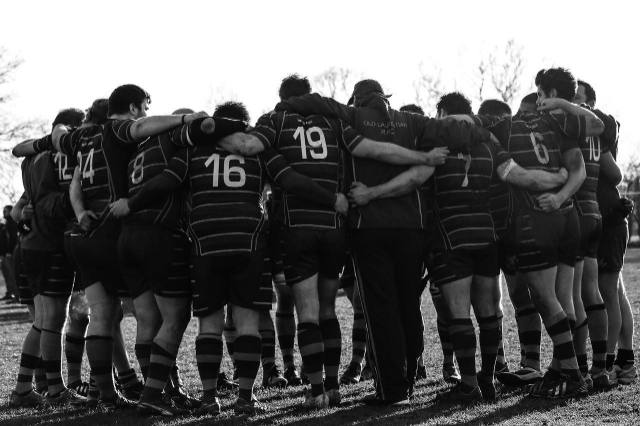 A sports team hugging together in circle representing an engaged team of people who will be on the pitch