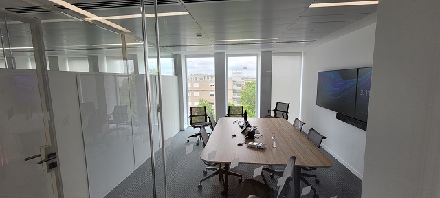 A 6x4m room with a big central table and glass walls