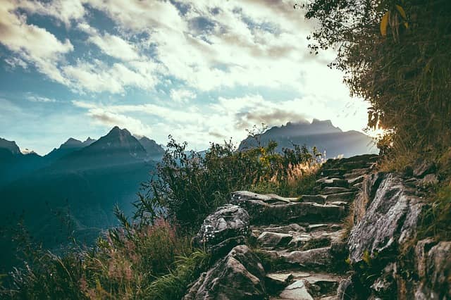 Photo of a mountain path where we can guess the sun will appear at the next turn. Design-Level Event Storming is a step by step workshop that leads to great outcome.