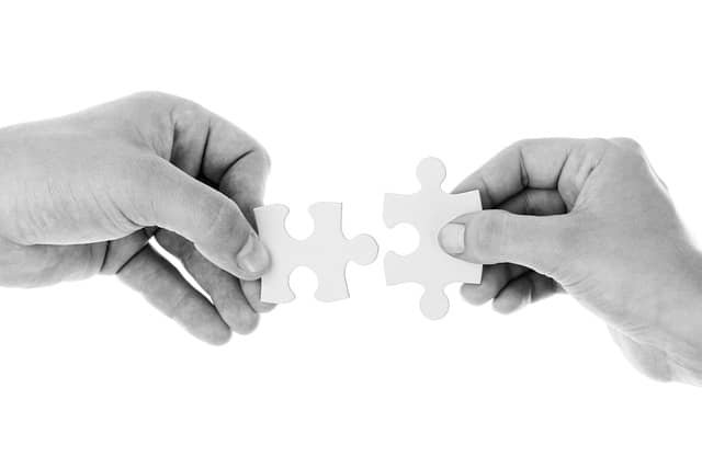 Photo of 2 hands bringing together 2 pieces of a puzzle. You now have all the pieces to run a successful remote Event Storming workshop.